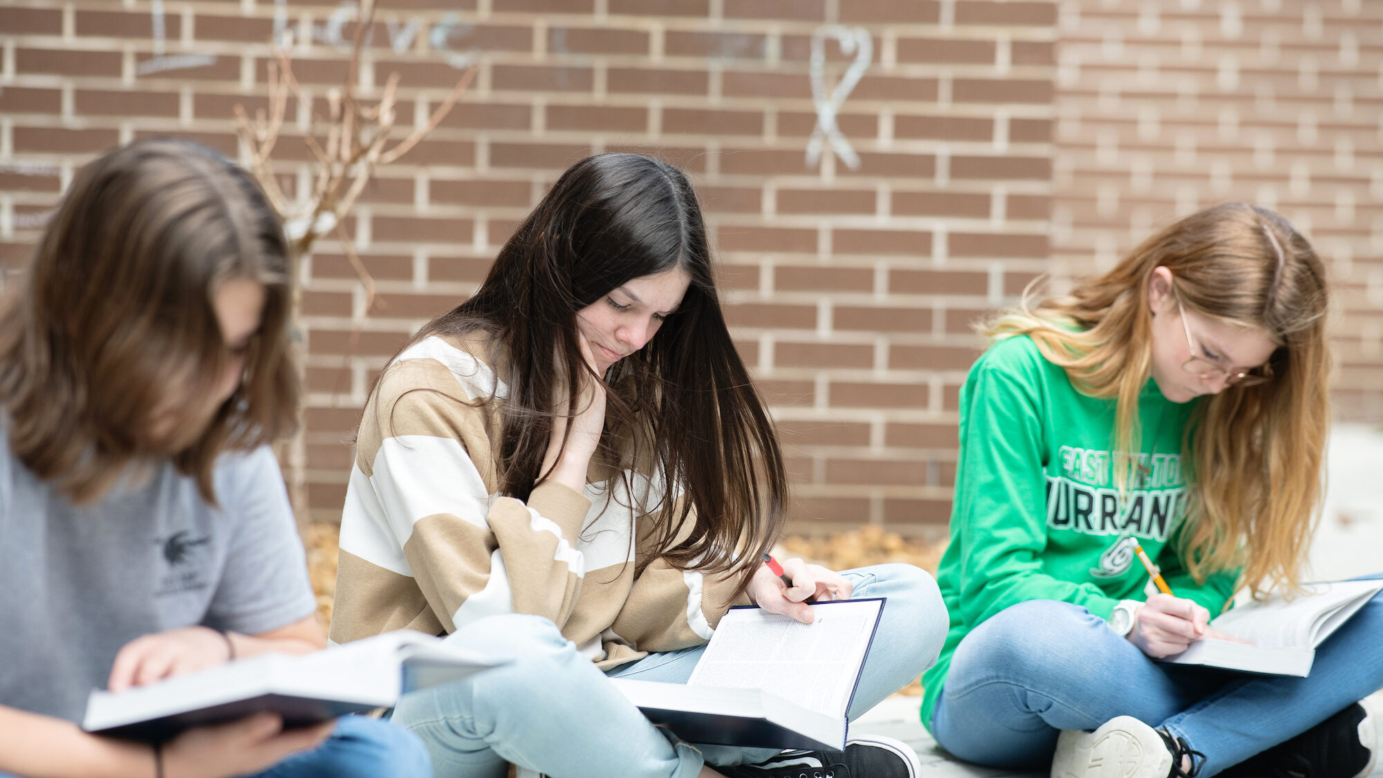 three students holding and reading their bibles